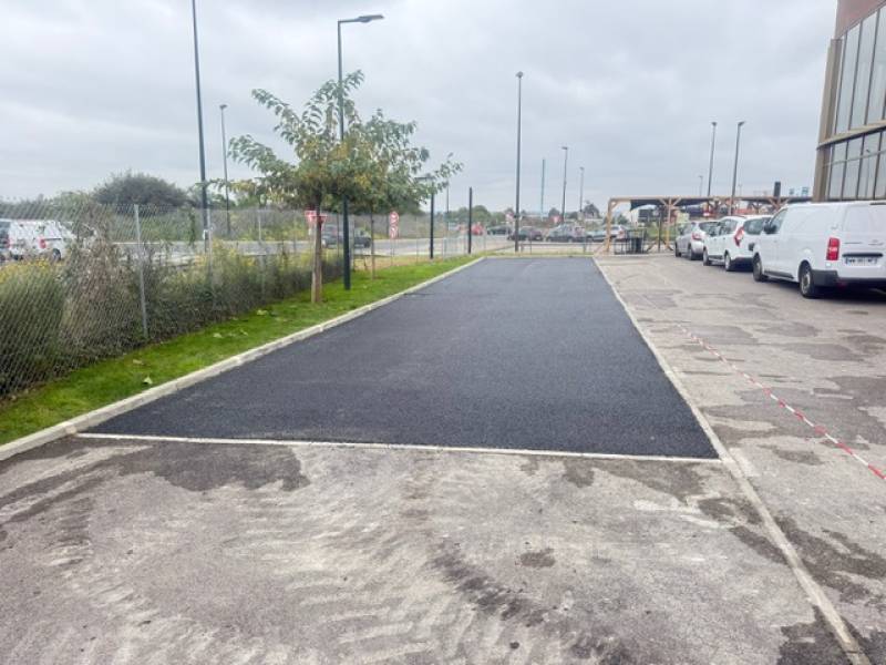 Stationnement d'une enseigne commerciale en enrobé à chaud noir drainant 